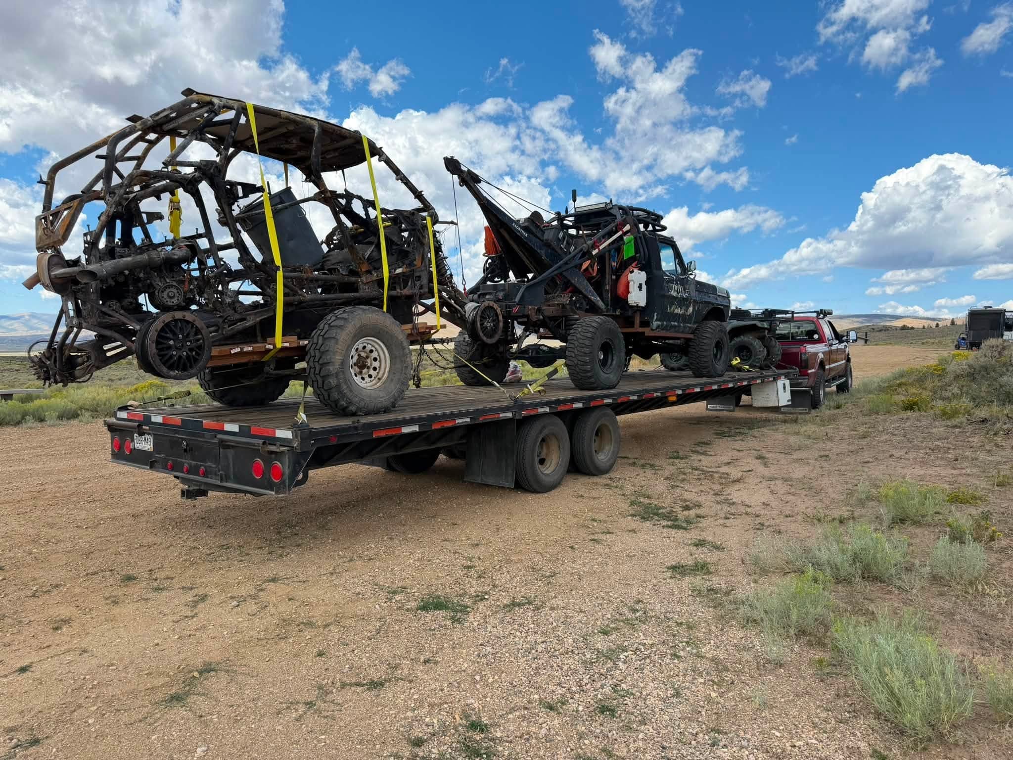 Recovery rig transporting a damaged buggy across desert terrain