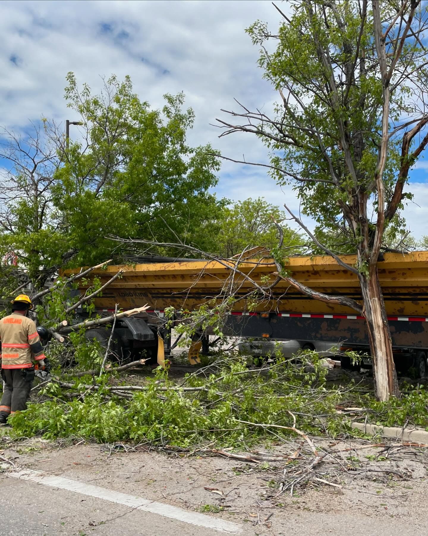 Worker in an orange vest clearing debris from under a yellow beam