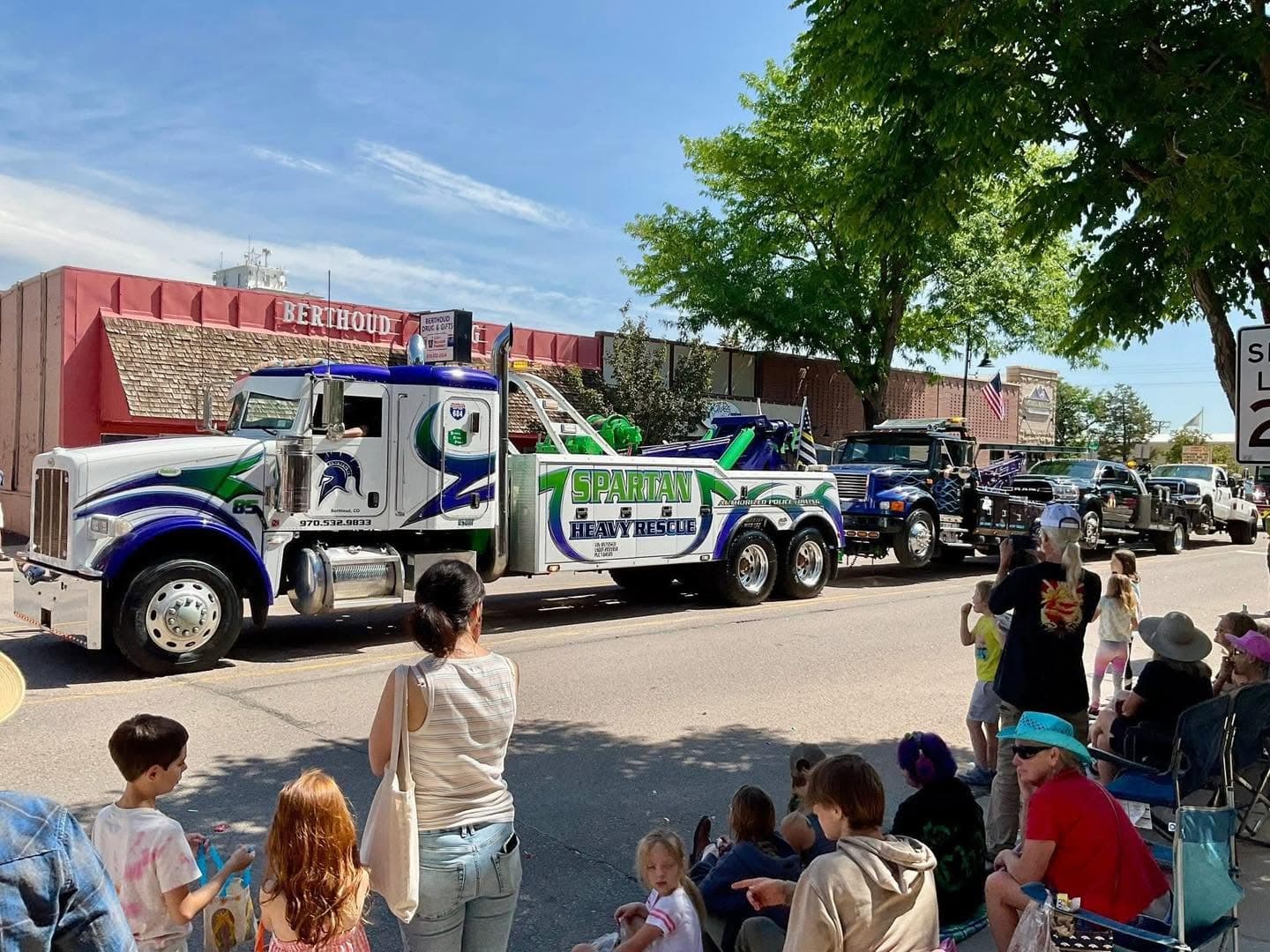 Heavy-duty wrecker in a public parade with a crowd watching