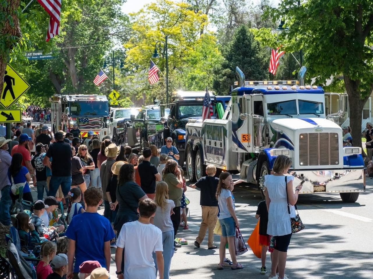 Spartan trucks in a town square with crowds and American flags
