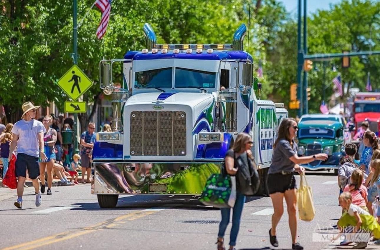 White and blue wrecker at a parade with spectators lining the street