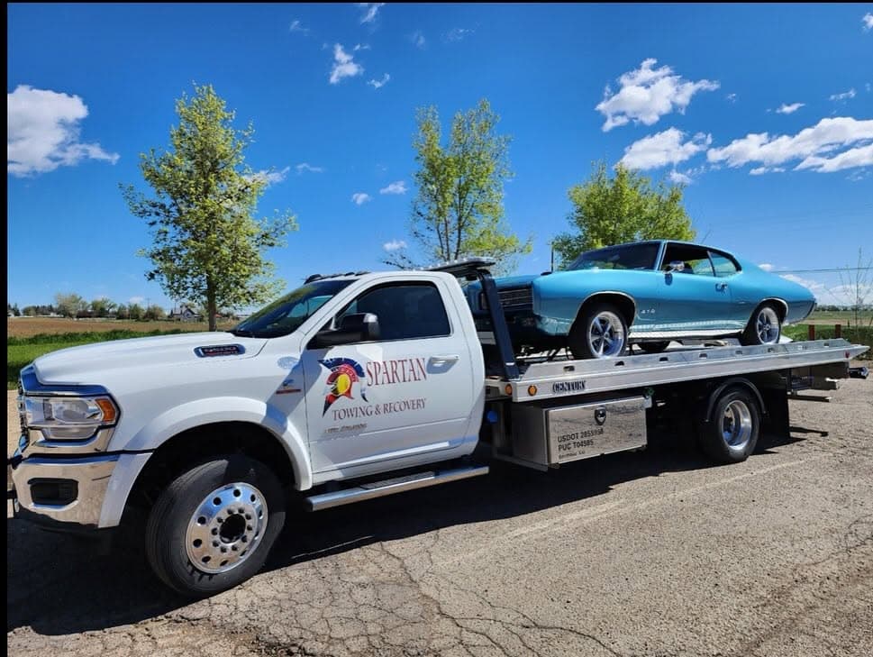 Flatbed carrying a light-blue classic muscle car