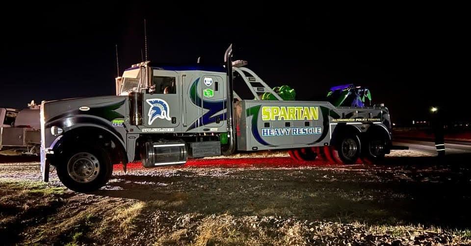 Spartan heavy-duty wrecker lit up at night