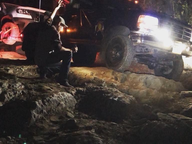 Spartan crew running a nighttime recovery on rocky terrain, headlights raking the scene